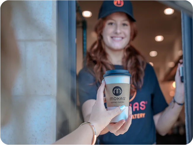 Drive-thru worker handing coffee to customer