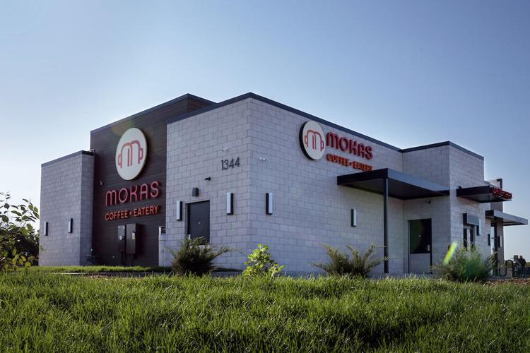 Mokas Coffee Eatery modern standalone building with a drive-thru and clean architectural design, located on a sunny day.